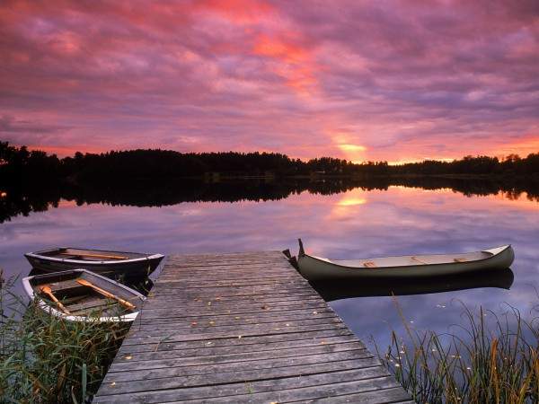 The nature of Sweden. Canoe tied to lakeside dock at sunset